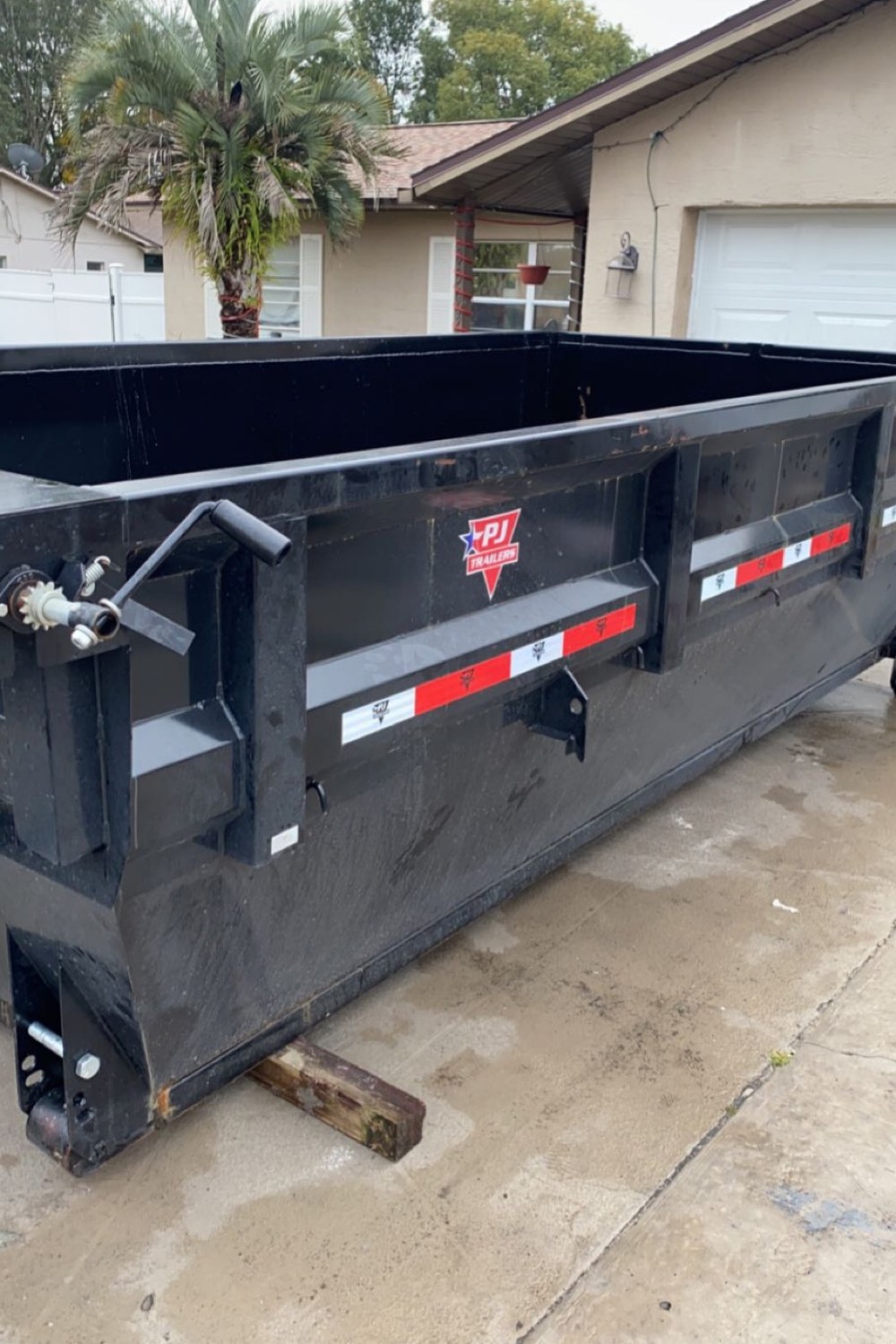 An empty Dump It container parked on a driveway in front of a house
