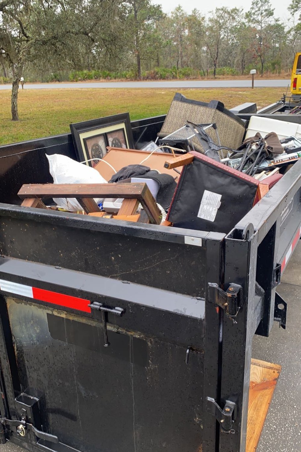 A Dump It container filled to the top with furniture, boxes and junk